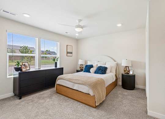A bedroom with a large bed and a window with a view of a fence and trees.
