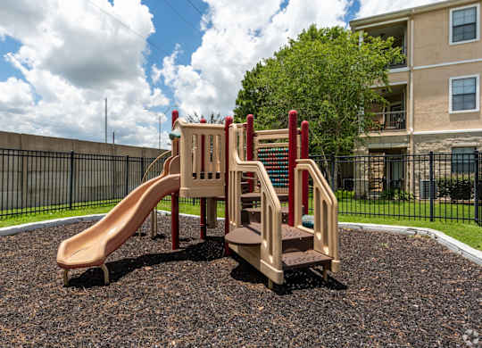 A playground with a slide, stairs, and a climbing wall.