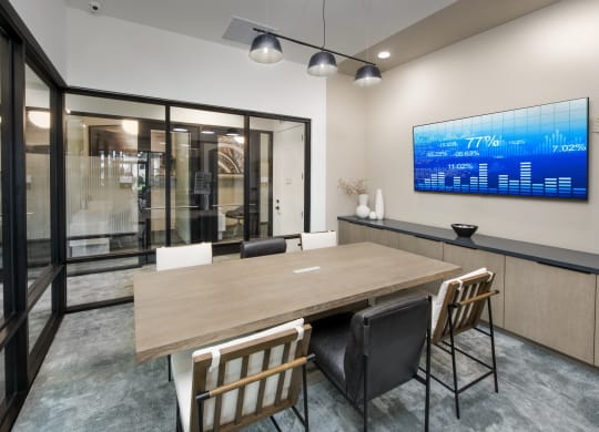a conference room with a wooden table and chairs and a monitor on the wall