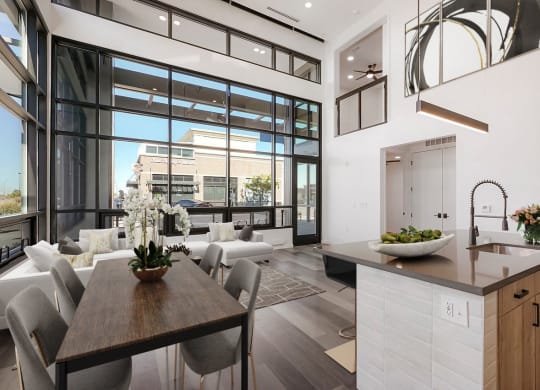 a kitchen and living room with large windows and a table