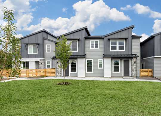 A row of modern houses with grey exteriors and wooden fences.