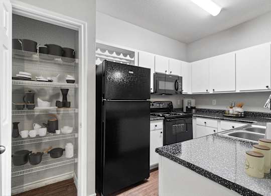 a kitchen with black appliances and white cabinets and granite counter tops
