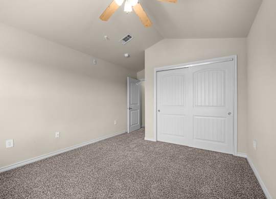 A room with a white door and a ceiling fan.