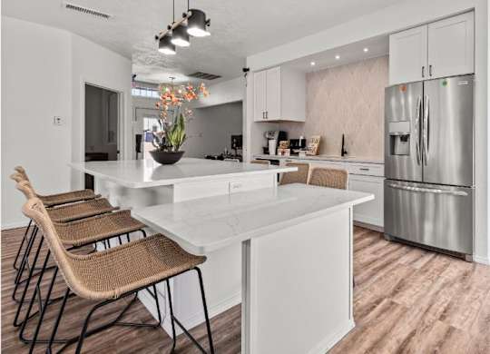 a kitchen with a large island and a stainless steel refrigerator