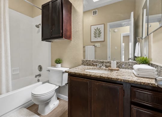 A white toilet sits in a bathroom with a brown cabinet.