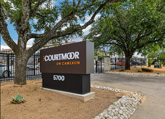A sign for Courtmoor on Cameron stands in front of a tree.