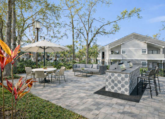 A patio with a table and chairs and a house in the background.