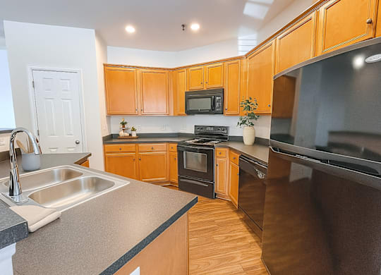 A kitchen with wooden cabinets and black appliances.