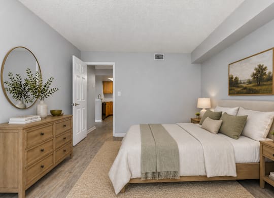 A bedroom with a large bed, a dresser, and a painting on the wall.