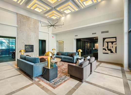 A large, modern living room with a high ceiling and a mix of blue and grey furniture.