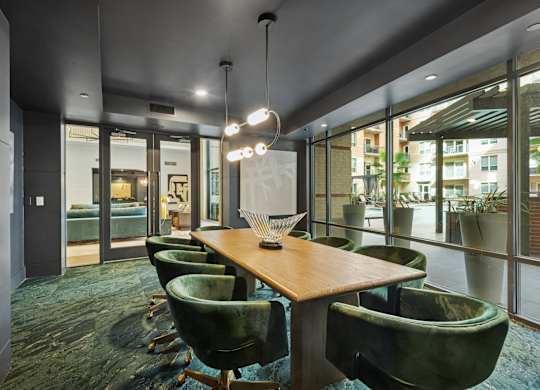 A conference room with a long table and green chairs.