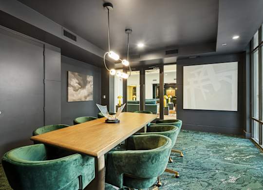 A conference room with a long table and green chairs.