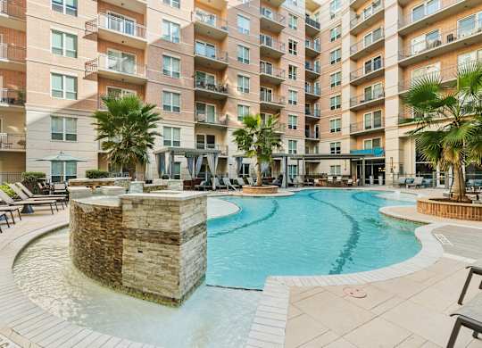 A large swimming pool in front of a multi-story apartment building.