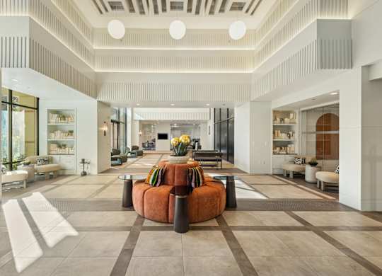 A spacious living room with a central orange sofa and a variety of seating options.