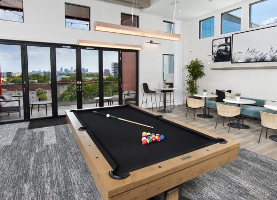 a billiards table in a clubhouse with a view of a patio and windows