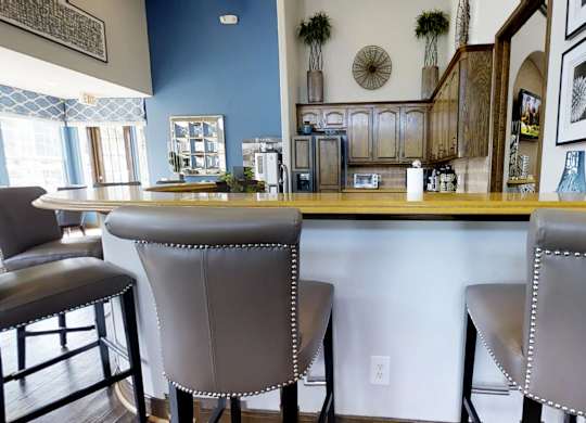 Two grey bar stools are placed in front of a bar.