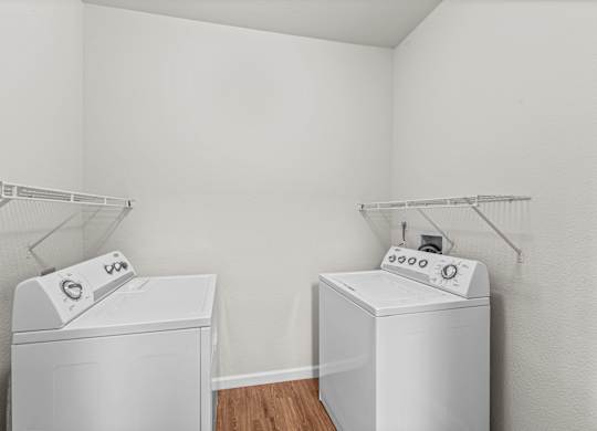 two white washers and dryers in a room with white walls and wood floor
