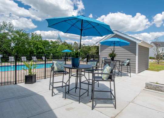 A blue umbrella is on a table outside a house.