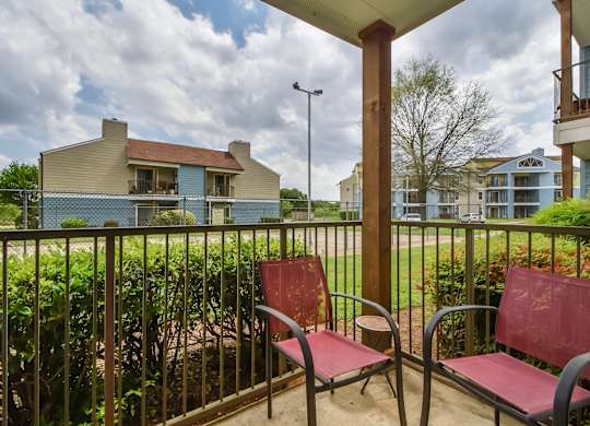 Two red chairs are on a patio.