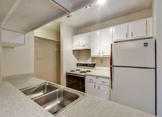 A kitchen with white cabinets and a stainless steel sink.