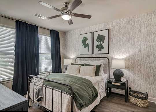 A bedroom with a bed, nightstand, and two pictures on the wall.