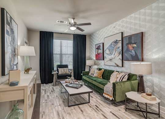 A living room with a green couch and a ceiling fan.