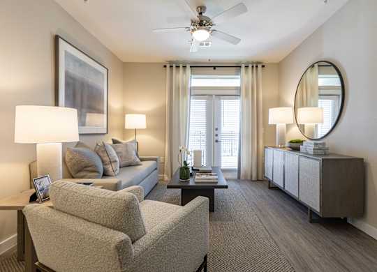 A well-lit living room with a grey sofa, two chairs, and a coffee table.