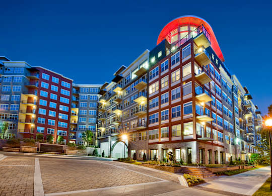 A modern multi-story building with a red and blue top is illuminated at night.
