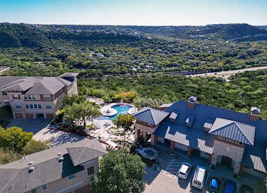 A large house with a pool in the middle of a wooded area.