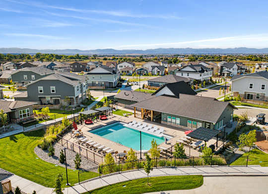 A large swimming pool surrounded by a black fence and a grassy area with a few trees.