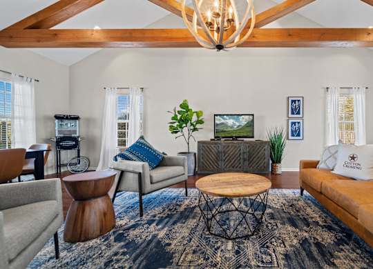 A living room with a brown couch, a coffee table, and a chandelier.