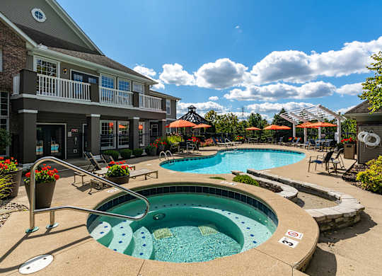 A large outdoor swimming pool with a hot tub in the middle of it.