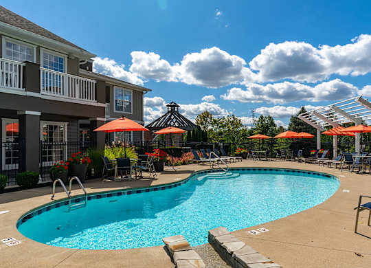A large swimming pool surrounded by lounge chairs and umbrellas.