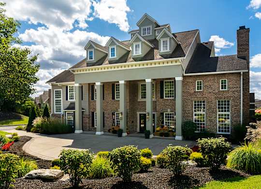 A large house with a front porch and a landscaped yard.