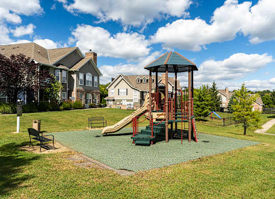 A playground with a green slide and a red swing set.