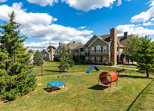 A playground with a red slide and blue table is in the foreground of a residential area.