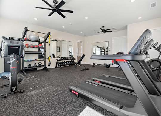 A spacious home gym with a treadmill, weights, and mirrors.