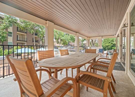 a patio with a wooden table and chairs