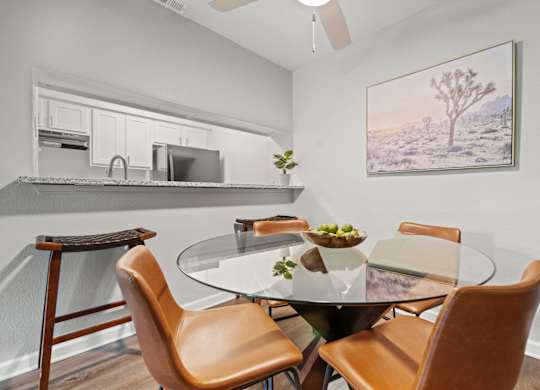 a dining area with a glass table and four chairs