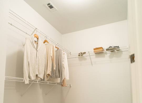 A walk in closet with clothes hanging on a rail.