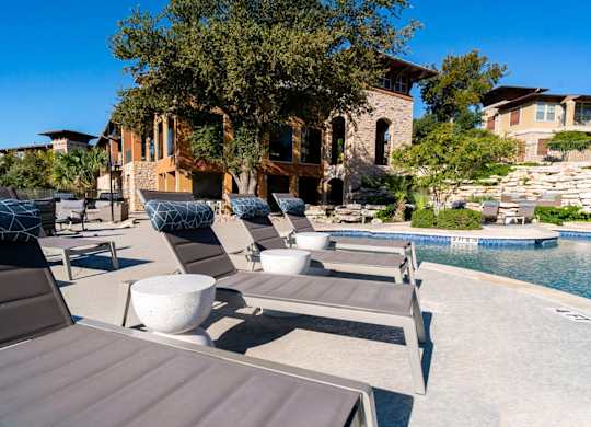 A poolside lounge area with sunbeds and a stone wall.