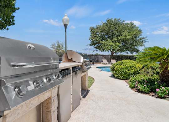 A large outdoor grill is on a patio next to a pool.