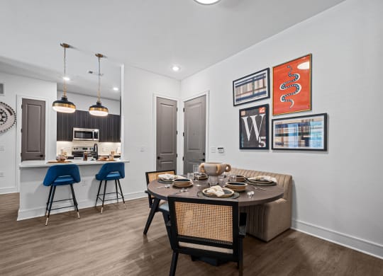 a dining area with a table and chairs and a kitchen in the background
