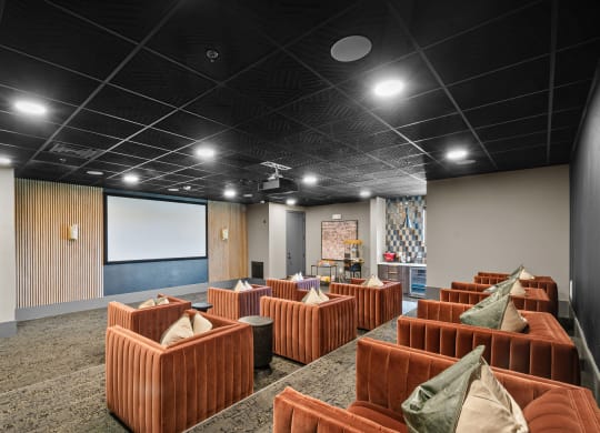 a large room with brown couches and a projector screen