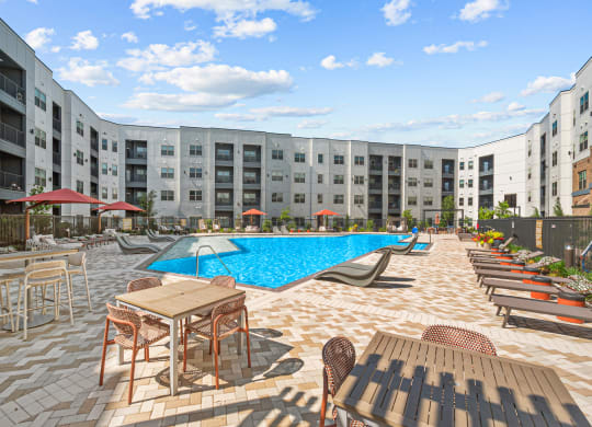 an outdoor pool with tables and chairs at an apartment building