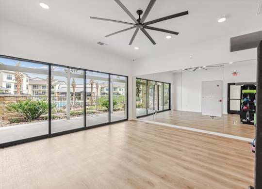 A room with a ceiling fan and sliding glass doors.