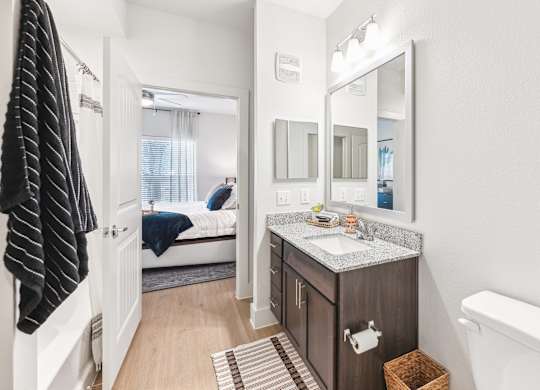 A bathroom with a toilet, sink, and mirror.