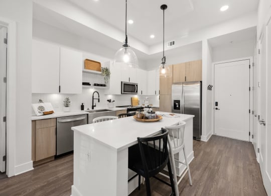 an open kitchen with a large white island with two black chairs