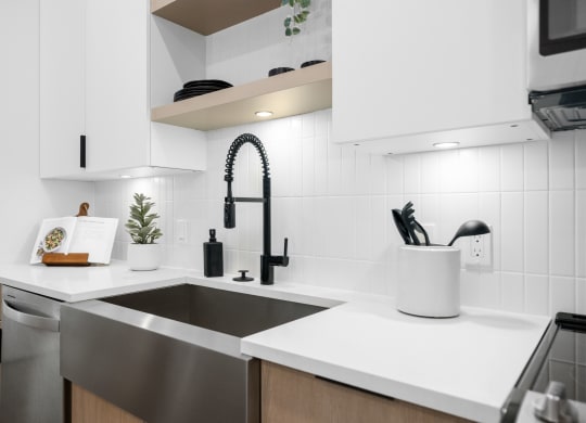 a kitchen with white counter tops and a black sink