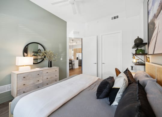 a bedroom with a large bed and a dresser with a mirror